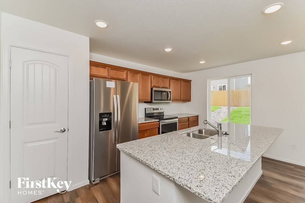 a kitchen with a granite counter top and a stainless steel refrigerator