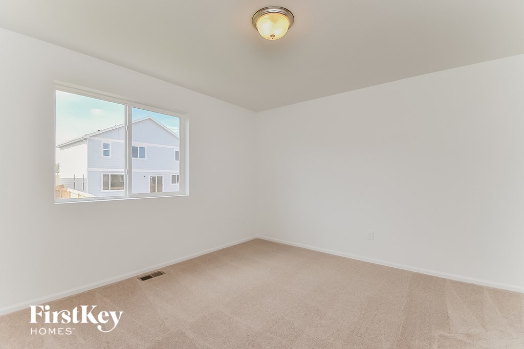 a spacious living room with a large window and beige carpet
