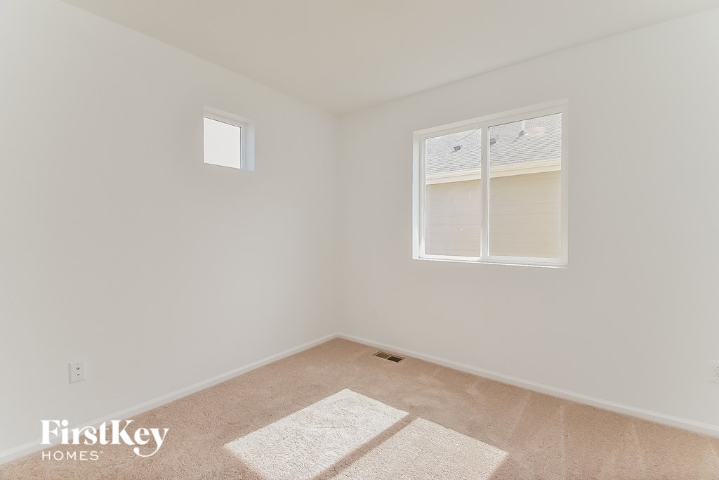 a bedroom with white walls and a window