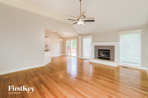 an empty living room with a fireplace and a ceiling fan