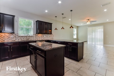 A kitchen with dark brown cabinets and a marble island.