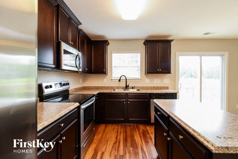 A kitchen with dark wood cabinets and a granite countertop.