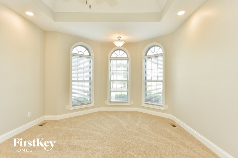 an empty living room with three windows
