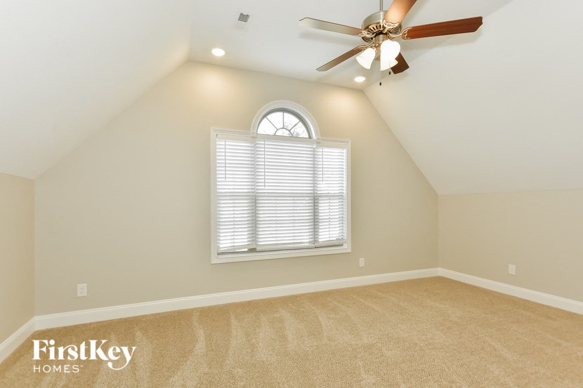 an attic bedroom with a window and a ceiling fan