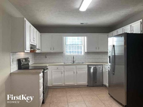 a kitchen with white cabinets and a stainless steel refrigerator