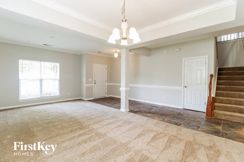 A spacious room with a staircase on the right side.