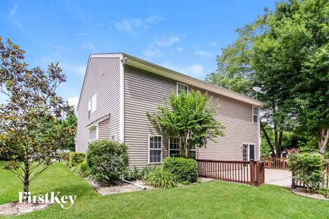 A house with a green lawn and trees in front of it.