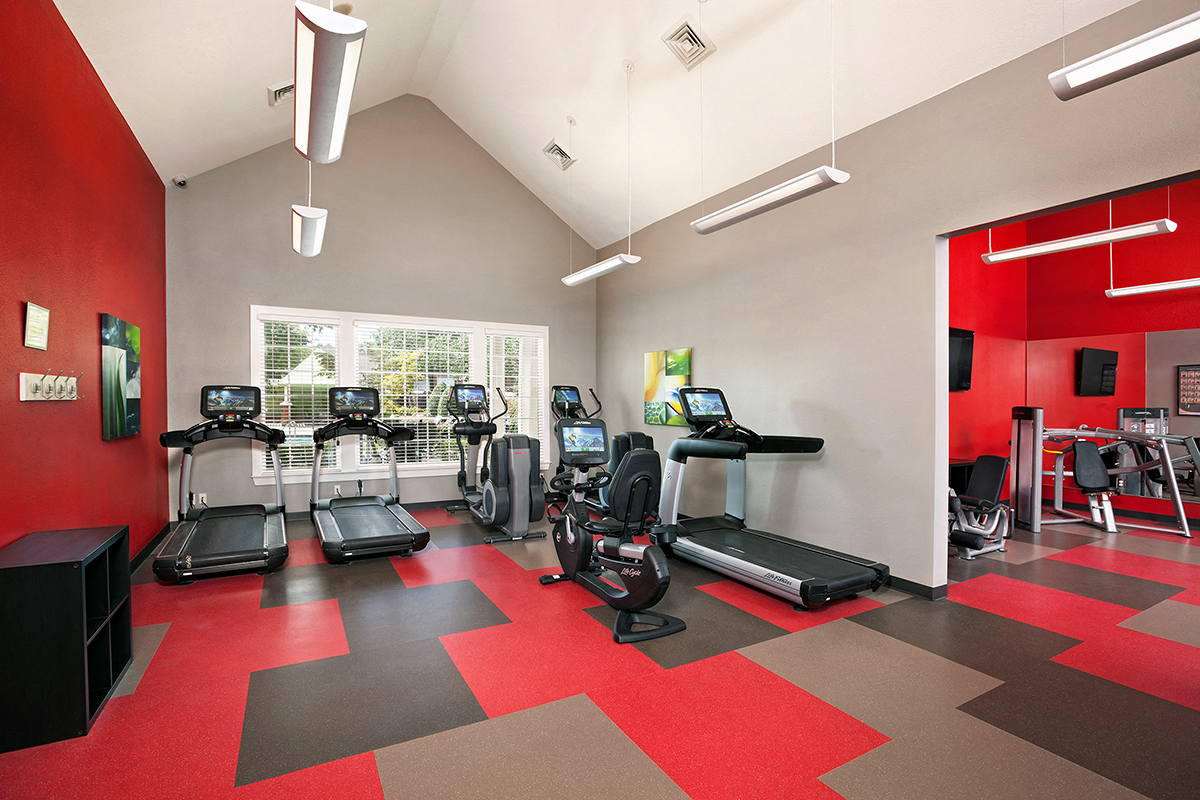 a gym with treadmills and other exercise equipment in a room with a window
