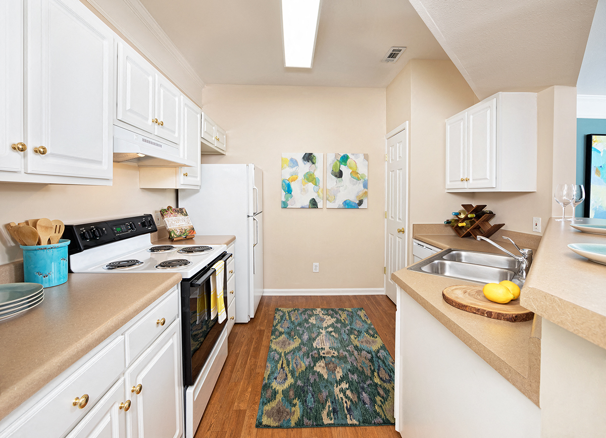 a kitchen with white cabinets and appliances and a rug