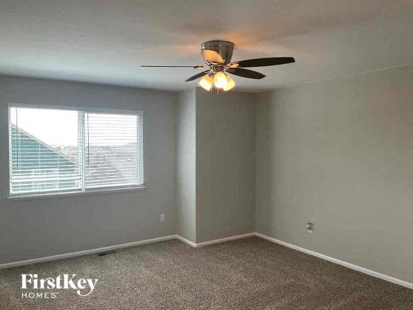 an empty bedroom with a ceiling fan and a window