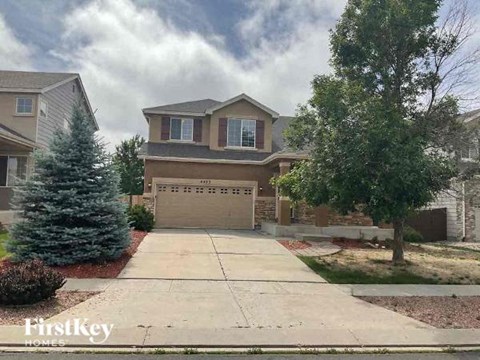 a house with a driveway and a tree in front of it