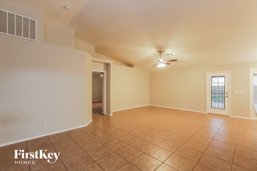 a empty living room with a ceiling fan and a tile floor