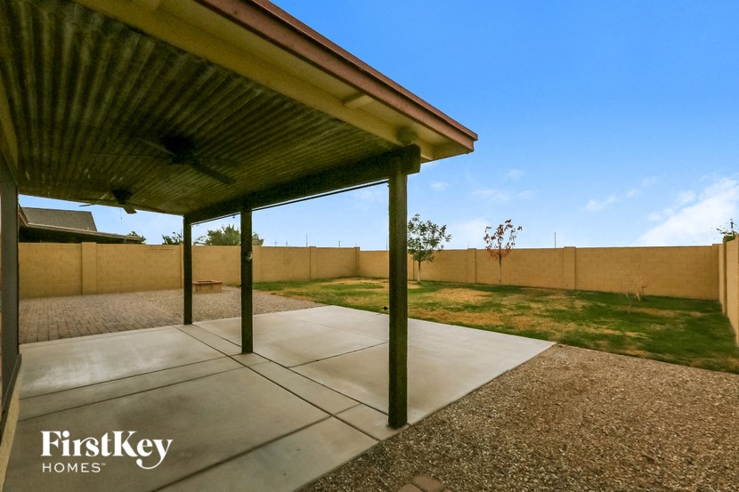 a covered patio in a backyard with a fence and grass