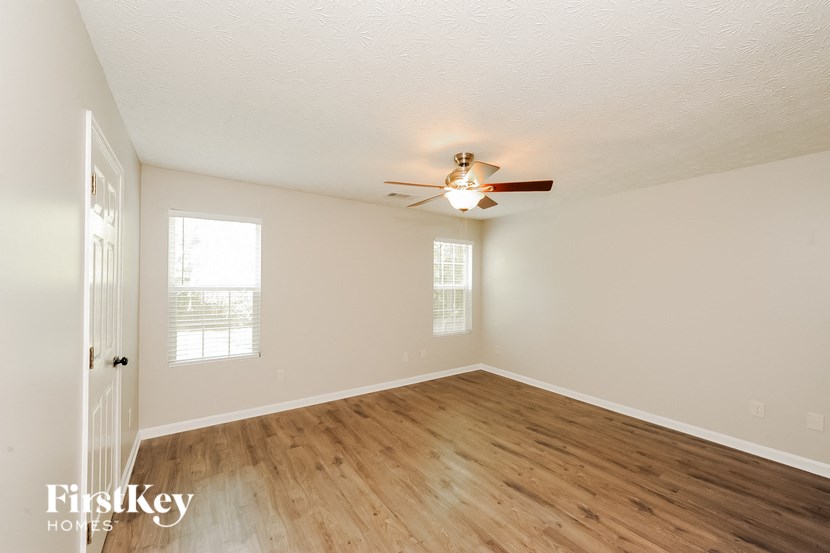 an empty living room with a ceiling fan and wood floors