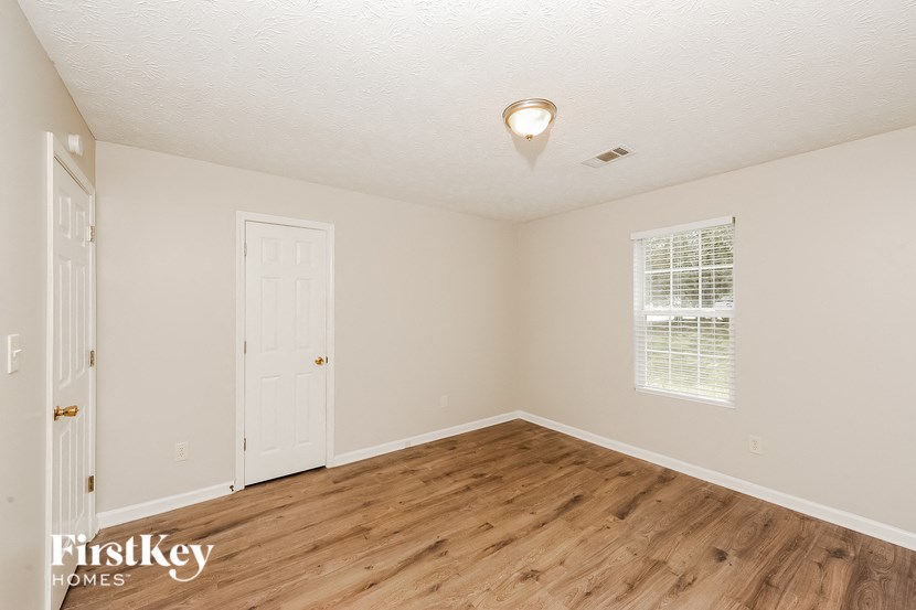 an empty bedroom with a wooden floor and a white door