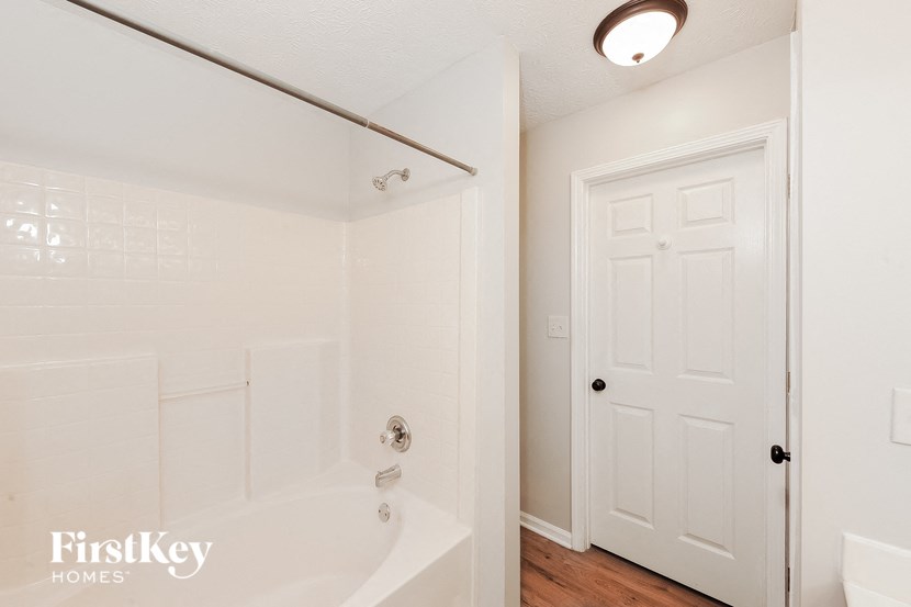 a white bathroom with a tub and a white door