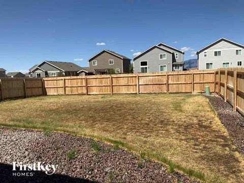 A backyard with a wooden fence and a grassy area.