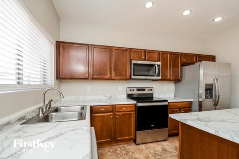 A kitchen with brown cabinets and a marble counter top.