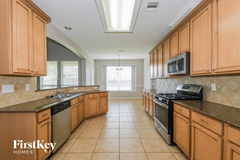 A kitchen with wooden cabinets and a tiled floor.