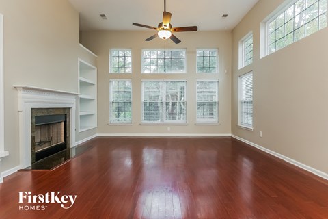 A spacious room with a fireplace and wooden floors.
