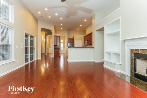 A spacious living room with wooden floors and a fireplace.