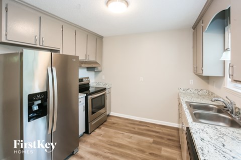 A kitchen with a stainless steel refrigerator and wooden floors.