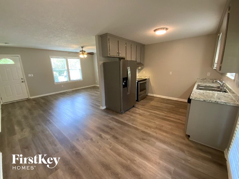 A kitchen area with wooden flooring and a refrigerator.