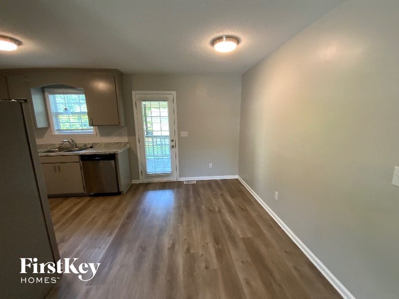 A room with wooden flooring and a door leading to a balcony.
