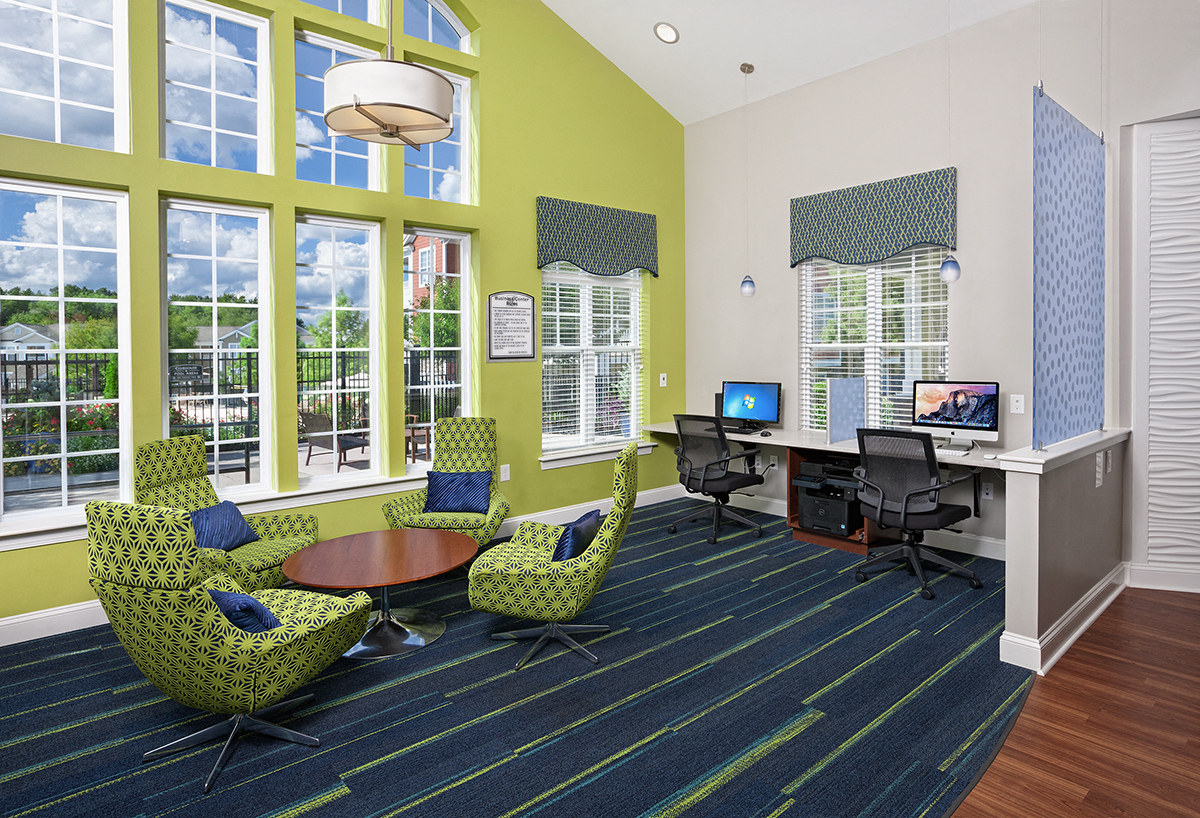 a lobby with green chairs and a desk with a computer