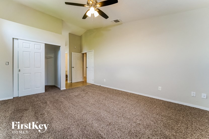 an empty living room with carpet and a ceiling fan