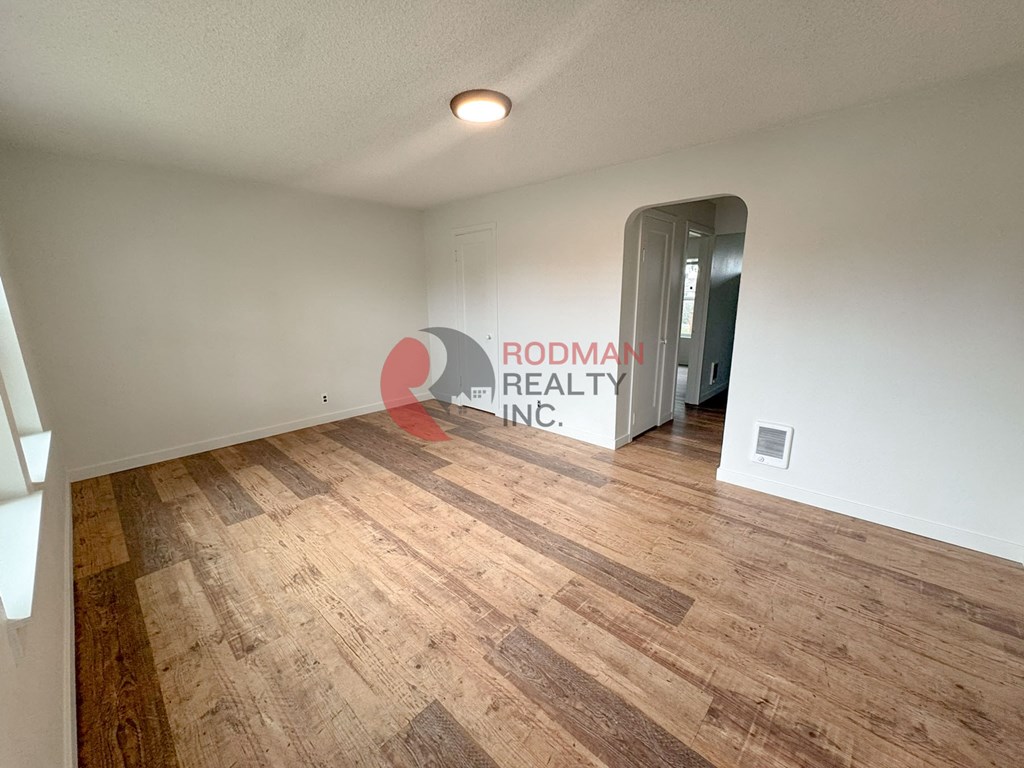 A room with wooden flooring and a doorway leading to another room.