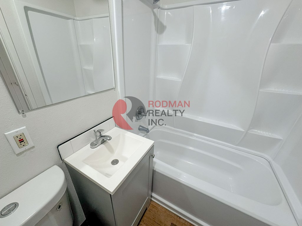 A white bathroom with a sink, toilet and bathtub.