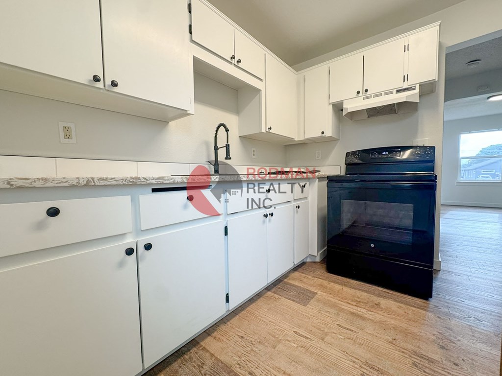 A kitchen with white cabinets and a black oven.