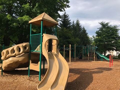 A playground with a yellow slide and a green structure.