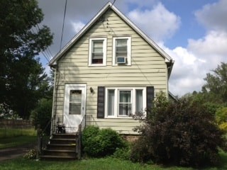 A small house with a white door and a staircase leading to the front door.