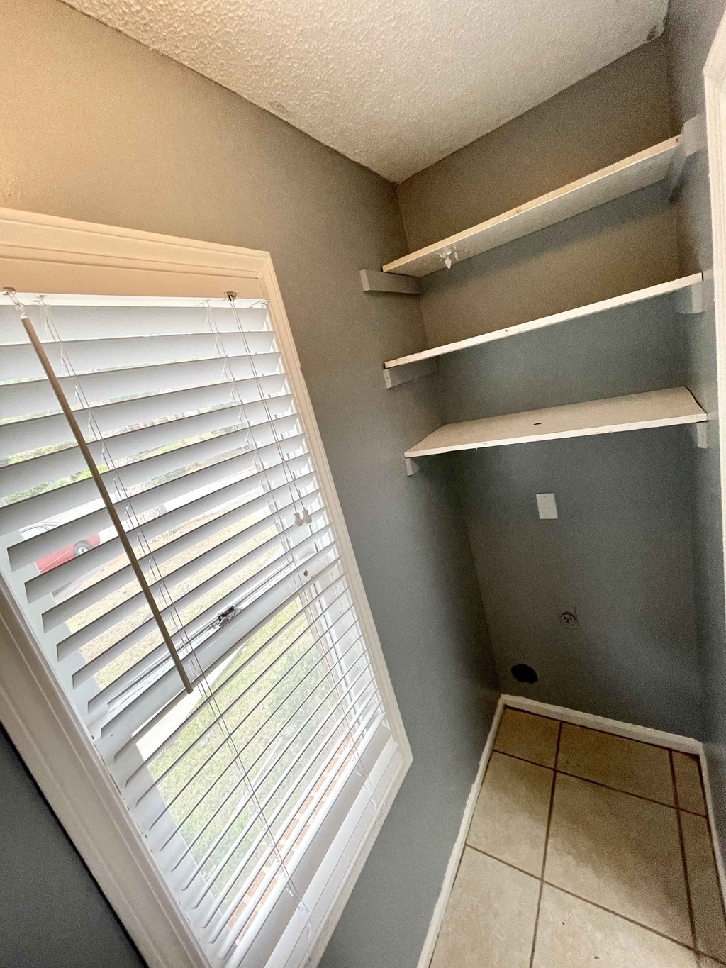 a walk in closet with white shelves and a window