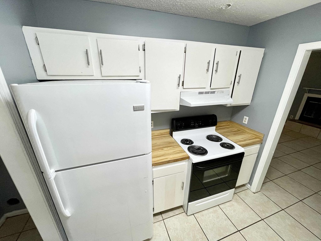 a kitchen with white cabinets and a stove and refrigerator