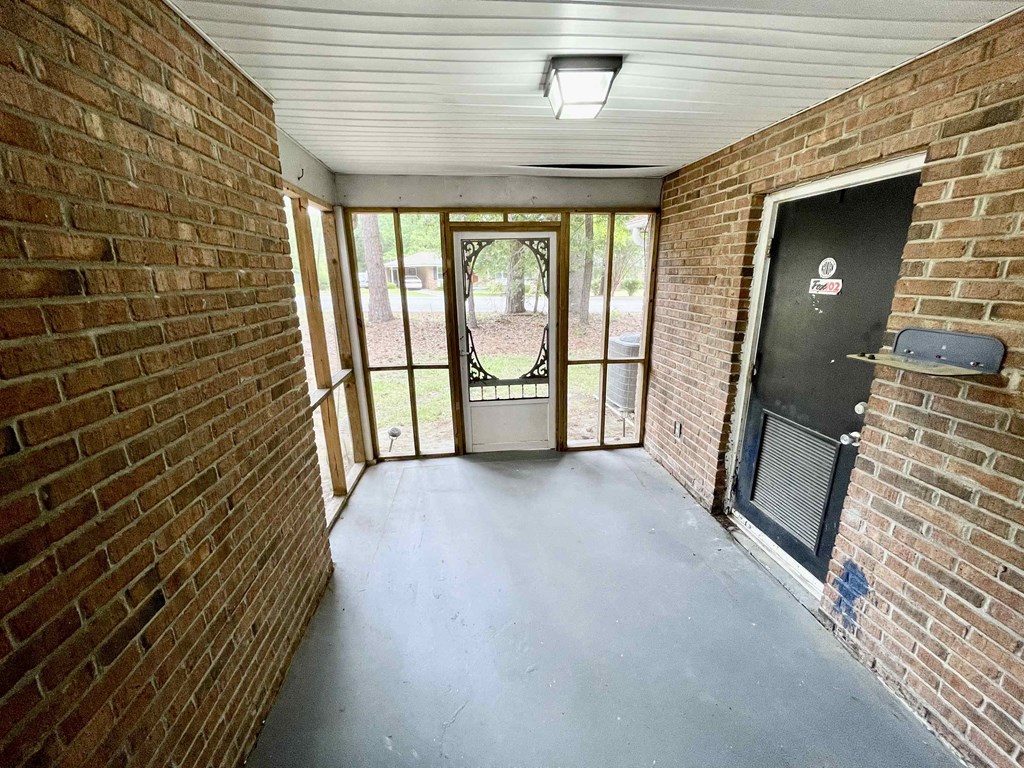 an empty porch with a brick wall and a glass door