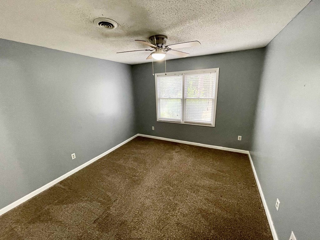 an empty room with carpet and a ceiling fan