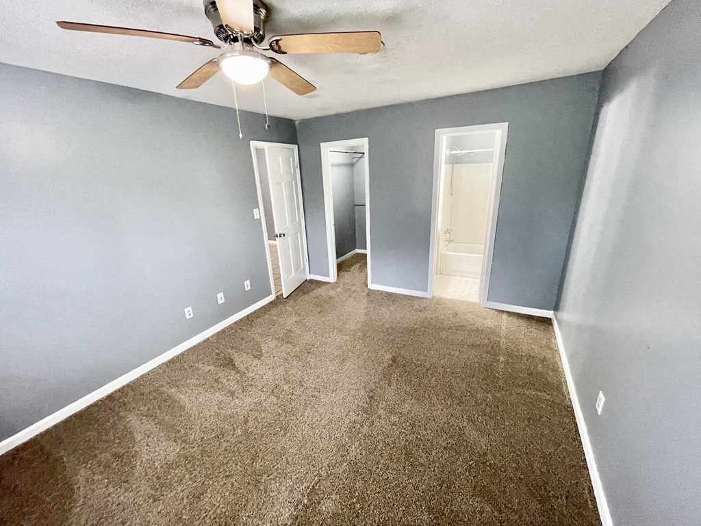 an empty room with blue walls and a ceiling fan