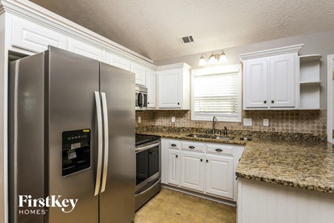 A kitchen with granite countertops and a stainless steel refrigerator.