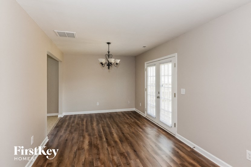 an empty living room with wood flooring and a chandelier