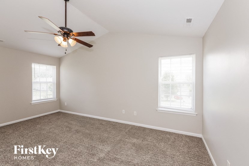 an empty room with a ceiling fan and two windows