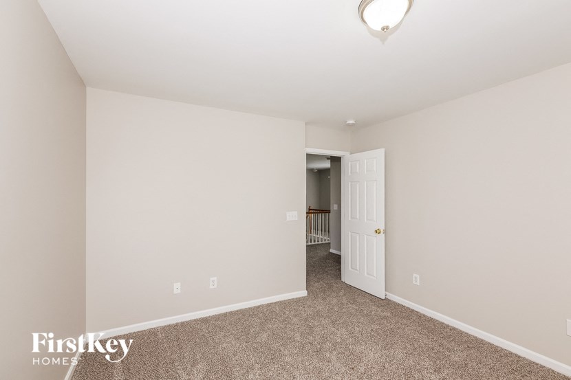 a bedroom with carpet and a door to a hallway