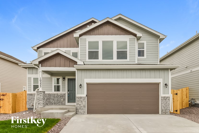 A modern two-story house with a garage door and a stone pillar.