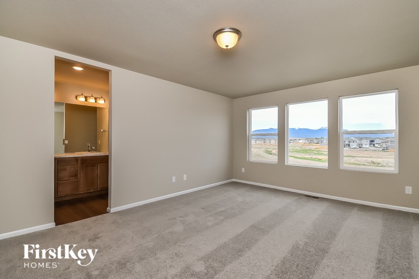 A spacious room with a carpeted floor and a view of the outdoors through the windows.