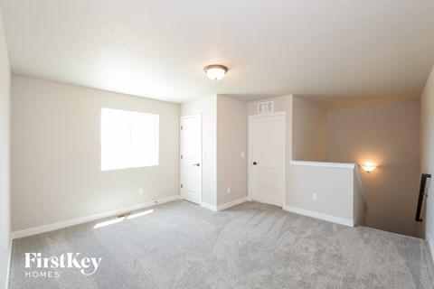 A spacious room with a carpeted floor and a window letting in natural light.