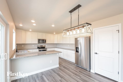 A modern kitchen with a stainless steel refrigerator and a hanging light fixture.