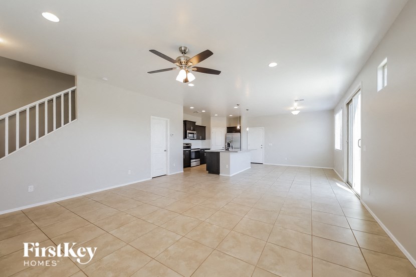 an empty living room and kitchen with a ceiling fan