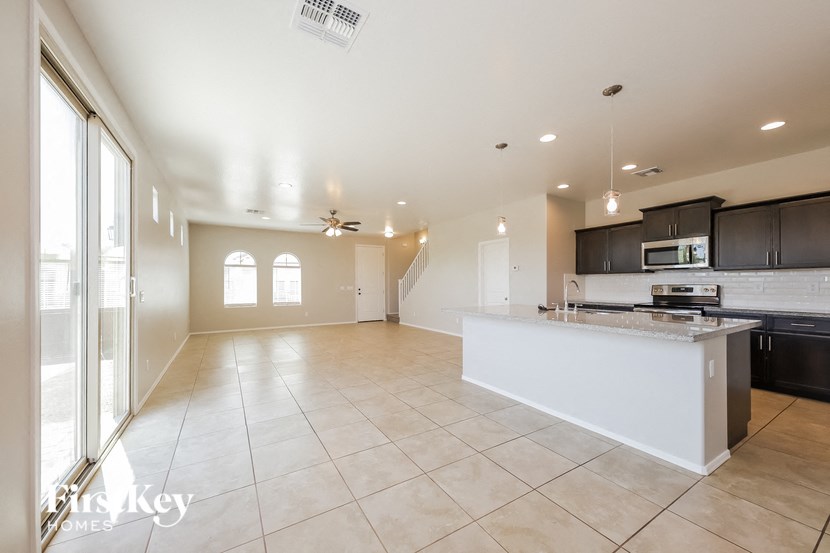 an open kitchen and living room with tile flooring